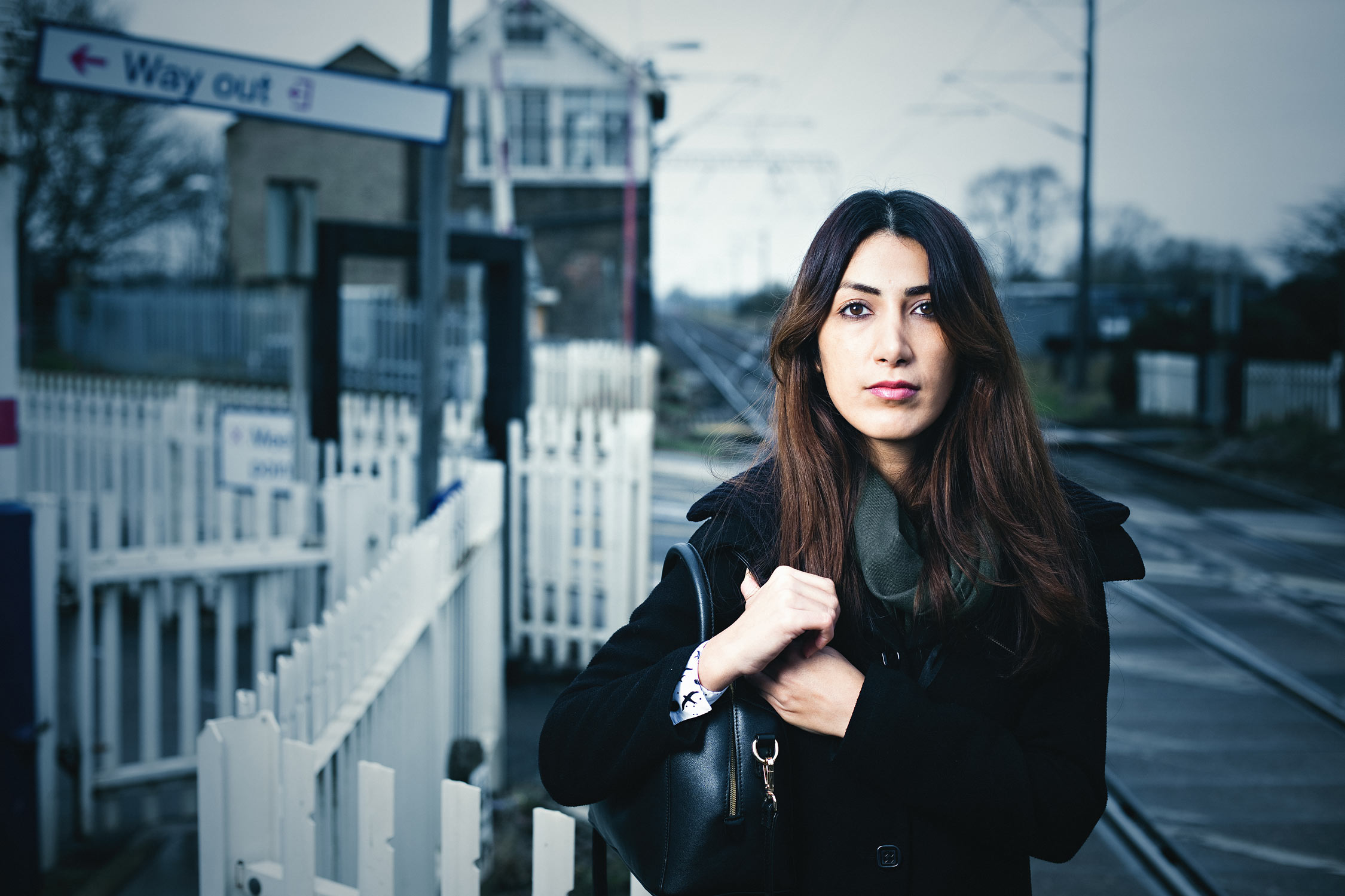 Moody advertising portrait of a young business woman waiting at a train station.