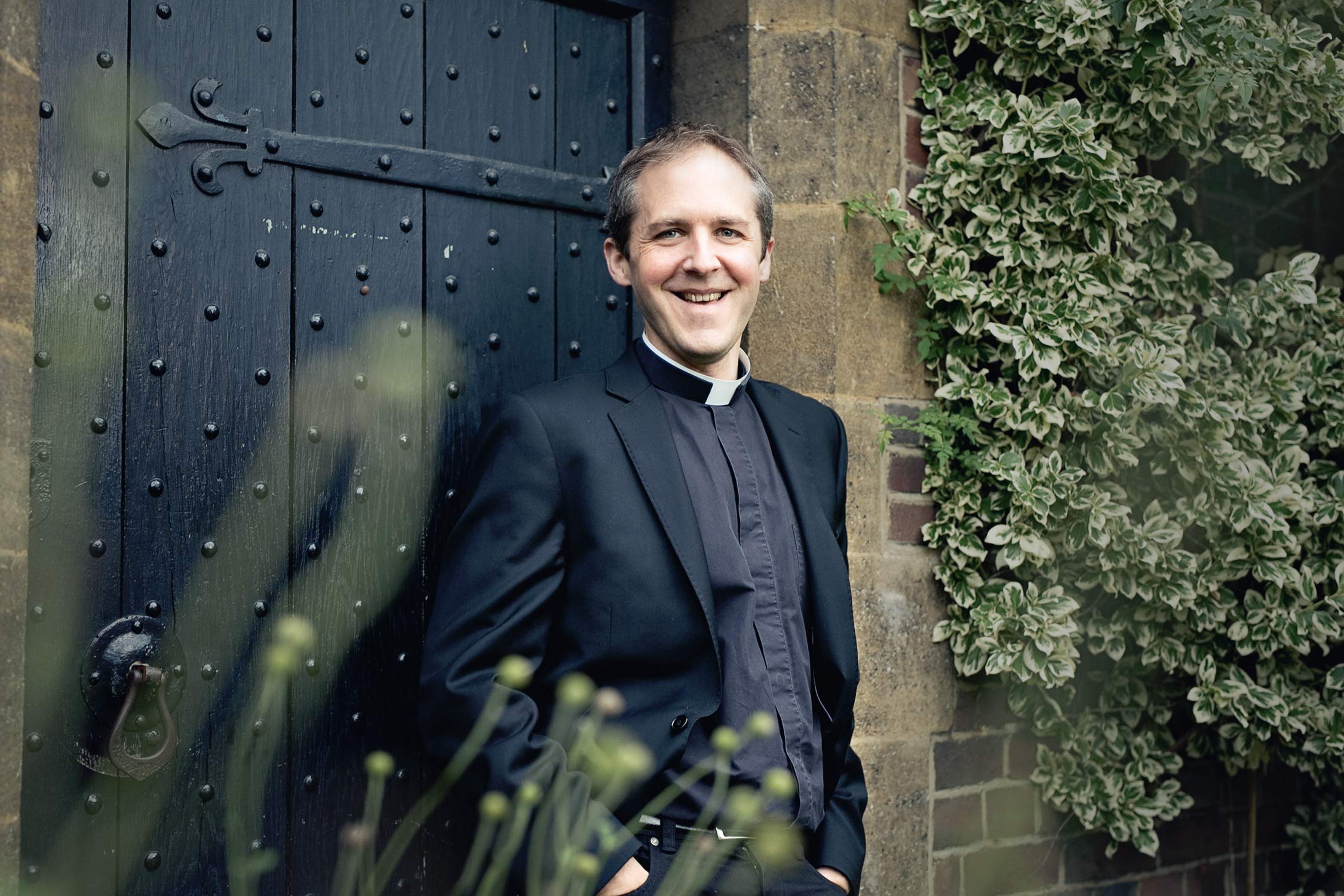professional standing portrait of a male academic in the garden of Westcott House, University of Cambridge.