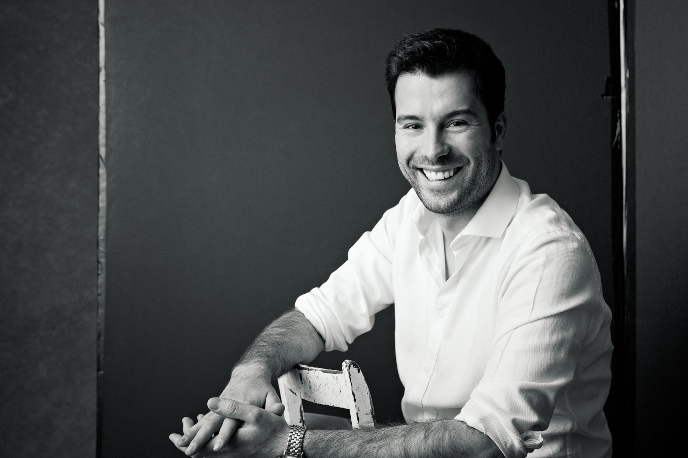 Modern studio portrait photography of a smiling man in black and white.