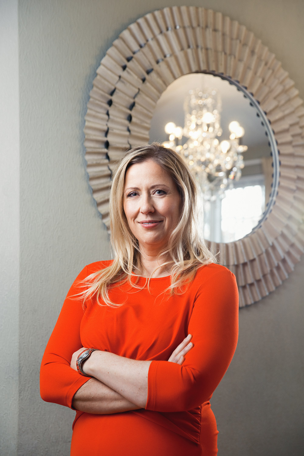 Professional location headshot of a property entrepreneur standing my an attractive mirror.