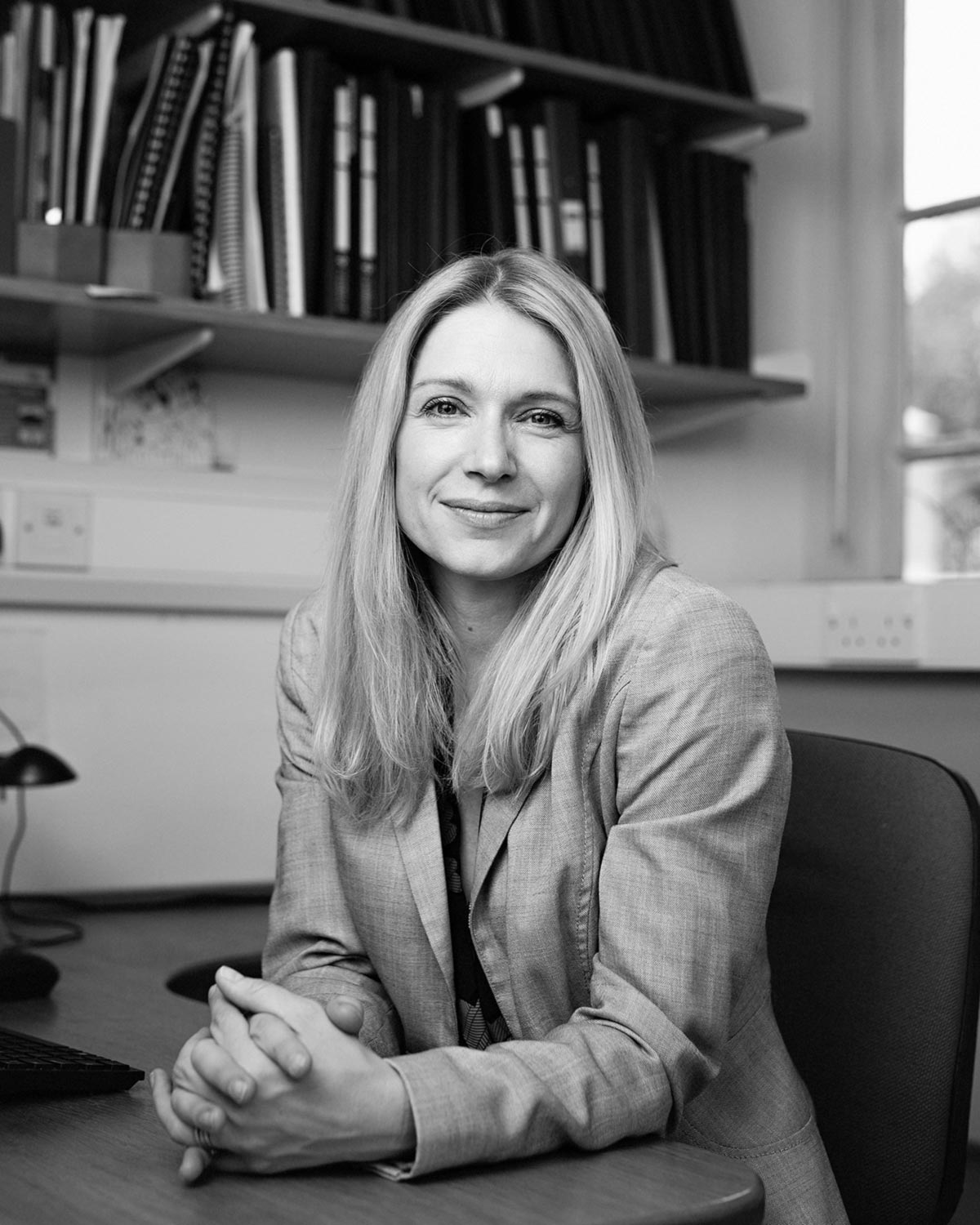 Black and white professional headshot portrait of a female academic shot on location at the University of Cambridge.